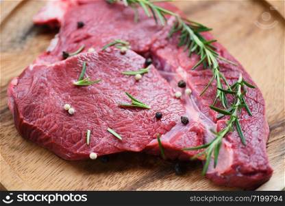 Raw beef meat rosemary on wooden cutting board on the kitchen table for cooking beef steak roasted or grilled with ingredients herb and spices , Fresh beef animal protein