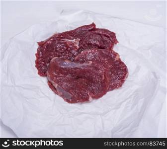 raw beef pieces on white paper, top view