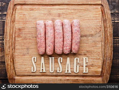 Raw beef sausages on wooden kitchen board with letters below.