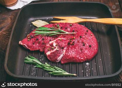 raw beef steak on a black quart pan, top view