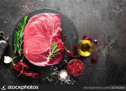 Raw beef steak on black background with cooking ingredients. Fresh beef meat. Top view