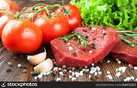 Raw beef steak on cutting board with vegetables and spices on brown wooden background. Beef steak, tomato, salad, garlic, rosemary, spice.. Raw beef steak with vegetables and spices