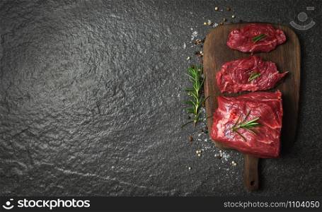 Raw beef steak with herb and spices rosemary / Fresh meat beef sliced on wooden cutting board background