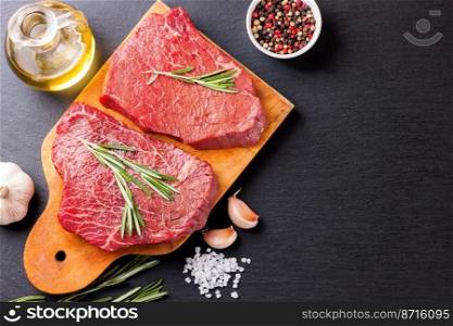 Raw beef steak with spices and ingredients for cooking on cutting borard and slate background. Top view.. raw beef steak with spice