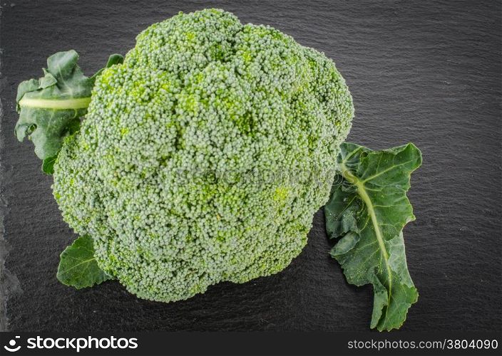 Raw broccoli on black chalkboard. Background with free text space.