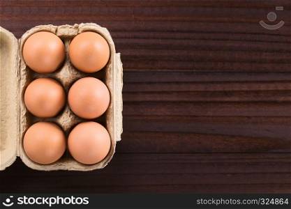 Raw brown eggs in egg box or carton, photographed overhead with copy space on the right (Selective Focus, Focus on the top of the eggs). Raw Brown Eggs in Egg Box or Carton