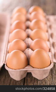 Raw brown eggs in egg box or carton (Very Shallow Depth of Field, Focus on the front of the first eggs). Raw Brown Eggs in Egg Box or Carton
