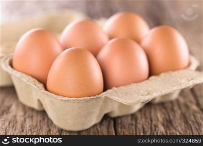 Raw brown eggs in egg box or carton (Very Shallow Depth of Field, Focus on the front of the first egg). Raw Brown Eggs in Egg Box or Carton