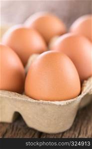 Raw brown eggs in egg box or carton (Very Shallow Depth of Field, Focus on the front of the first egg). Raw Brown Eggs in Egg Box or Carton