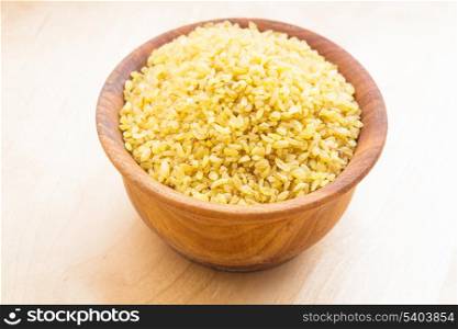 Raw bulgur in a wooden bowl on the table