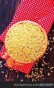 raw bulgur in bowl and on a table