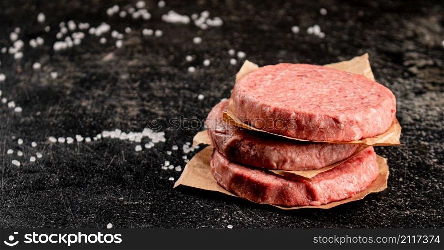 Raw burger of fresh meat on the table. On a black background. High quality photo. Raw burger of fresh meat on the table.