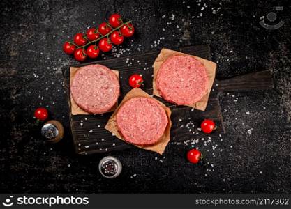 Raw burger on a cutting board. On a black background. High quality photo. Raw burger on a cutting board.