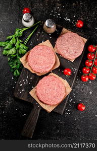 Raw burger on a cutting board. On a black background. High quality photo. Raw burger on a cutting board.