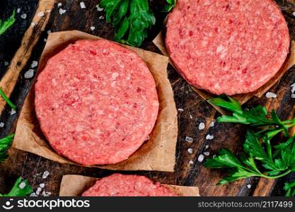 Raw burger on a cutting board with parsley and salt. Macro background. High quality photo. Raw burger on a cutting board with parsley and salt.