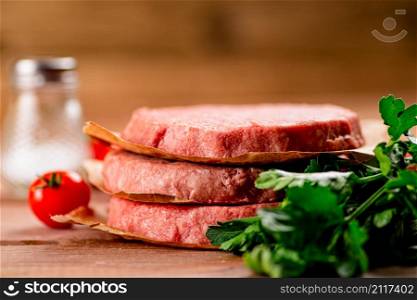 Raw burger with fresh tomatoes. On a wooden background. High quality photo. Raw burger with fresh tomatoes.