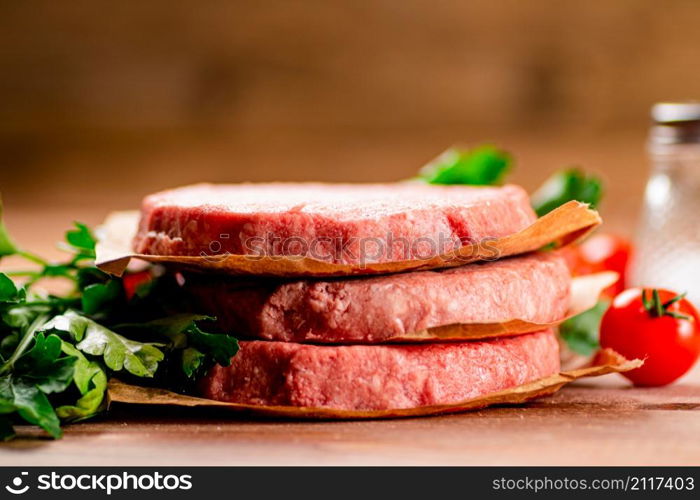 Raw burger with fresh tomatoes. On a wooden background. High quality photo. Raw burger with fresh tomatoes.