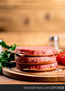 Raw burger with fresh tomatoes. On a wooden background. High quality photo. Raw burger with fresh tomatoes.