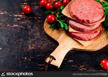 Raw burger with tomatoes and parsley. Against a dark background. High quality photo. Raw burger with tomatoes and parsley.