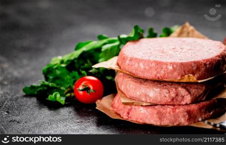 Raw burger with tomatoes and parsley. On a rustic background. High quality photo. Raw burger with tomatoes and parsley.