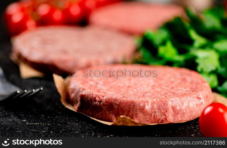 Raw burger with tomatoes and parsley. On a rustic background. High quality photo. Raw burger with tomatoes and parsley.