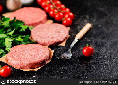 Raw burger with tomatoes and parsley. On a rustic background. High quality photo. Raw burger with tomatoes and parsley.