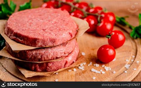 Raw burger with tomatoes. On a wooden background. High quality photo. Raw burger with tomatoes.