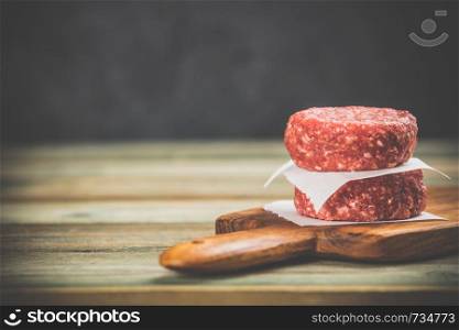 raw burgers - cutlets from organic beef meat on wooden background, space for text. raw burgers - cutlets from organic beef meat