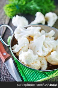 raw cauliflower in the metal bowl and on a table