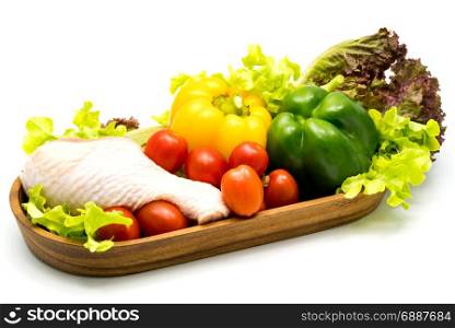 Raw chicken and vegetables in wooden tray on white background
