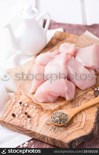 Raw chicken breast fillets with herbs over wooden board, selective focus