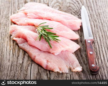raw chicken breast fillets with rosemary on wooden table