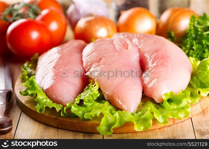 Raw chicken breast with vegetables on wooden table
