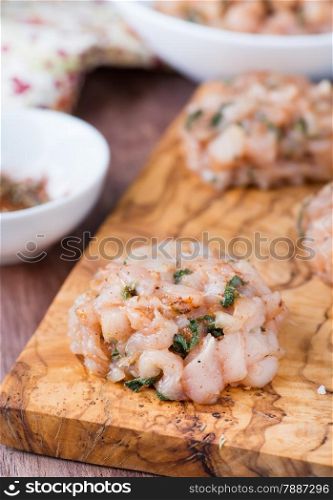 Raw chicken cutlets with herbs and seasoning on olive wood background, closeup, selective focus