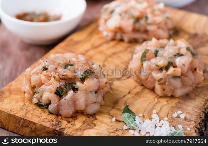 Raw chicken cutlets with herbs on olive wood background, selective focus