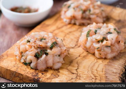 Raw chicken cutlets with herbs on olive wood background, selective focus