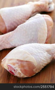 Raw chicken drumsticks on a wooden cutting board