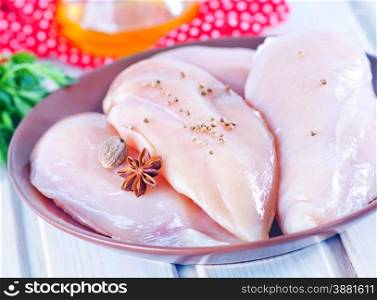 raw chicken fillet on plate and on a table