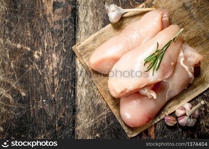 Raw chicken fillet with garlic and herbs. On wooden background.. Raw chicken fillet with garlic and herbs.