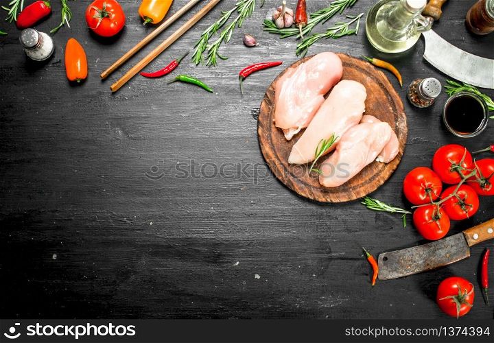 Raw chicken fillet with herbs and spices. On the black chalkboard.. Raw chicken fillet with herbs and spices.