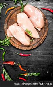 Raw chicken fillet with herbs and spices. On the black chalkboard.. Raw chicken fillet with herbs and spices.