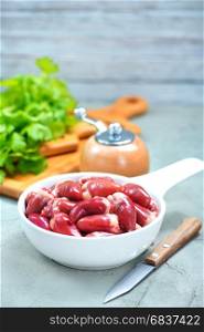 raw chicken hearts in bowl and on a table