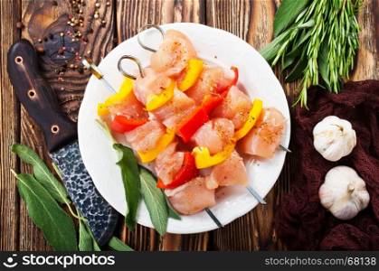 raw chicken kebab with vegetables on white plate