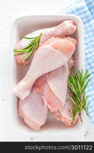 Raw chicken legs, fresh poultry drumsticks on white wooden table, top view