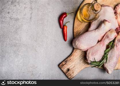 Raw chicken legs on cutting board for cooking on gray concrete background, top view