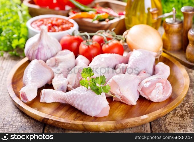 raw chicken legs on wooden plate