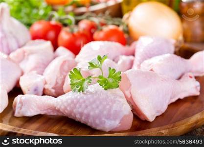 raw chicken legs on wooden plate