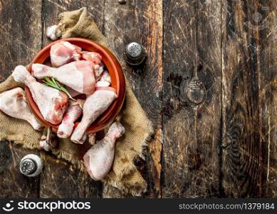 Raw chicken legs with garlic and spices in a bowl. On wooden background.. Raw chicken legs with garlic and spices in a bowl.