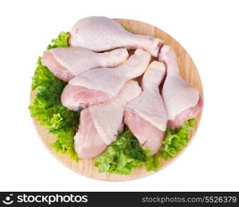Raw chicken legs with green salad on a wooden board