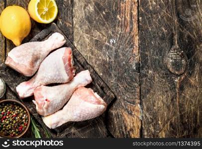 Raw chicken legs with spices and lemon. On wooden background.. Raw chicken legs with spices and lemon.